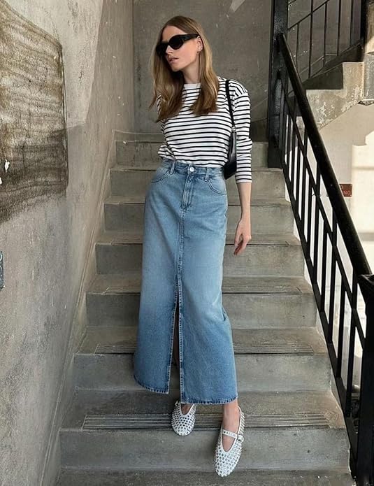 Woman in striped shirt and denim skirt standing on a staircase wearing a pair of flat shoes with square crystal