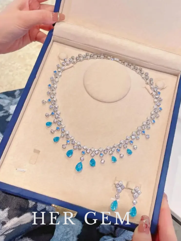 Necklace with blue stones in a jewelry box labeled 'HER GEM'.