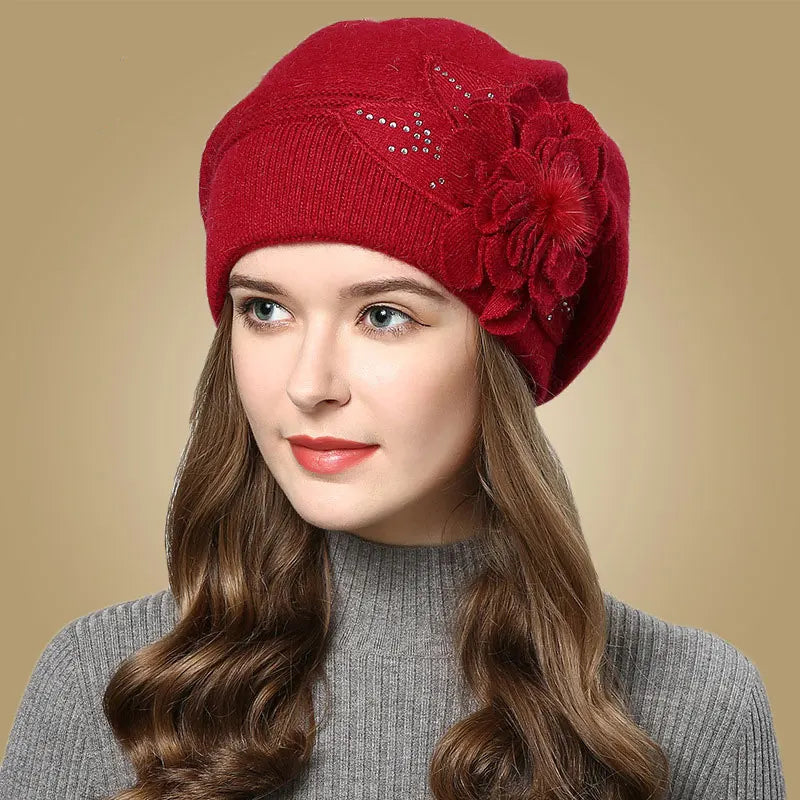Woman wearing a red knitted hat with floral details on a beige background