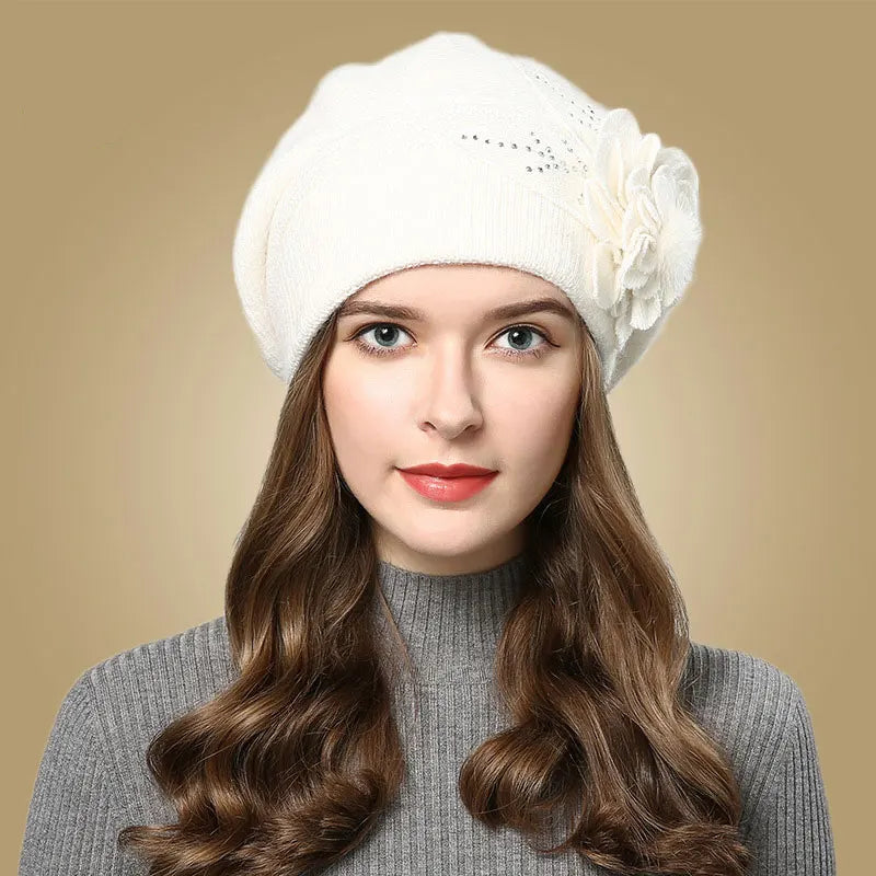 Woman wearing a white beanie with a flower on a beige background