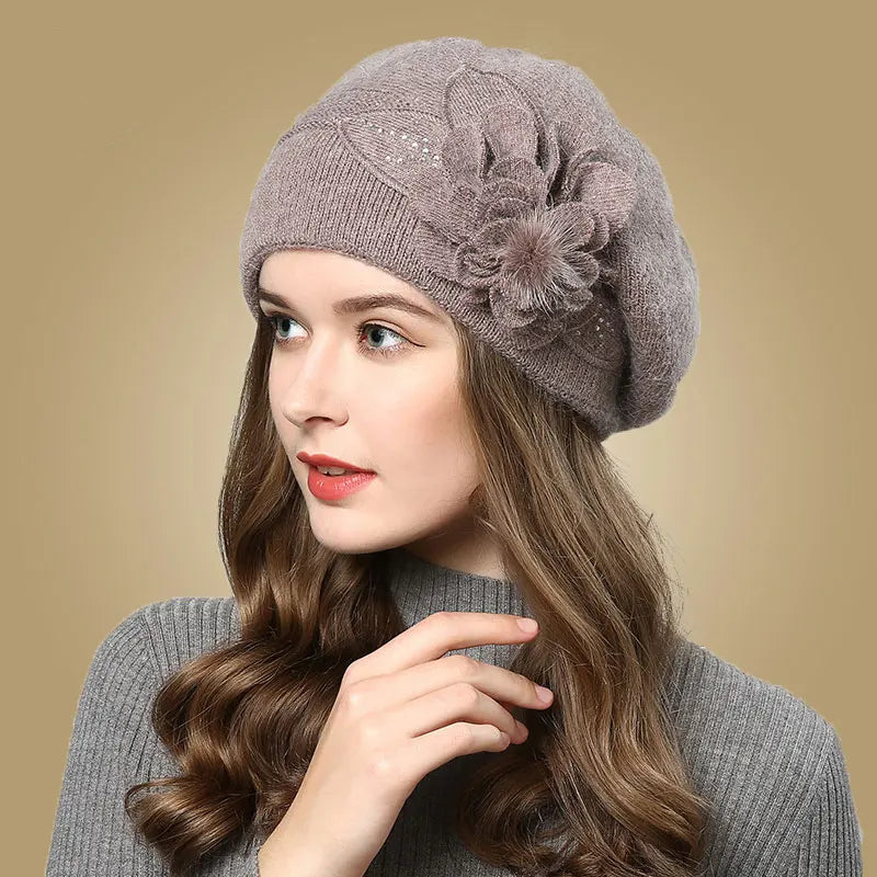 Woman wearing a gray knit beret with a decorative flower on a beige background
