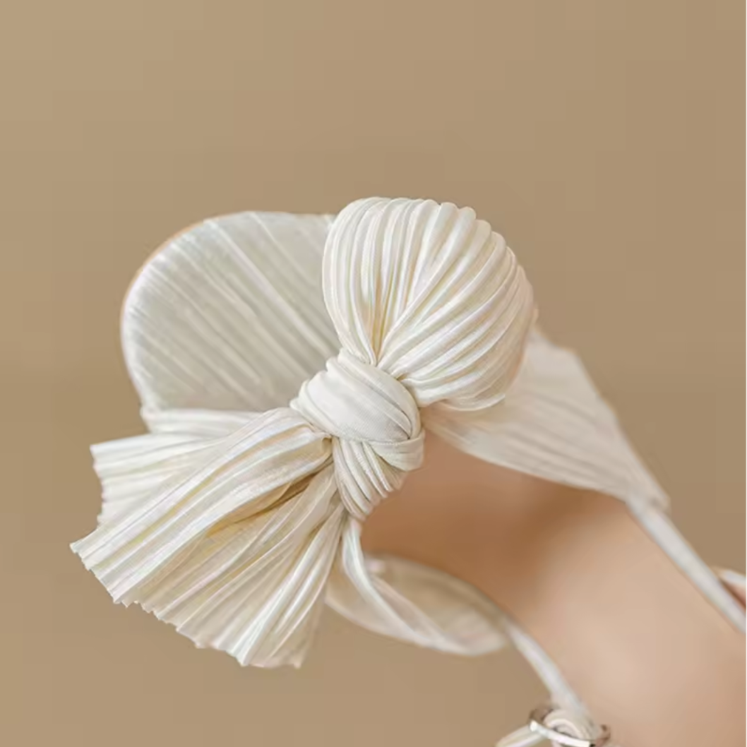 White pleated headband with a bow on a beige background