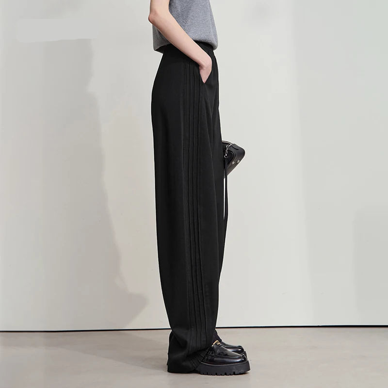Person wearing black pleated pants and black shoes against a white background