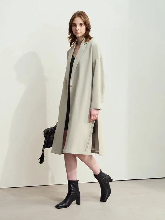 A woman modeling a beige AMII minimalist loose trench coat with a floral hydrangea print on the back, featuring a lapel collar and drop cuff design. - HER SHOP