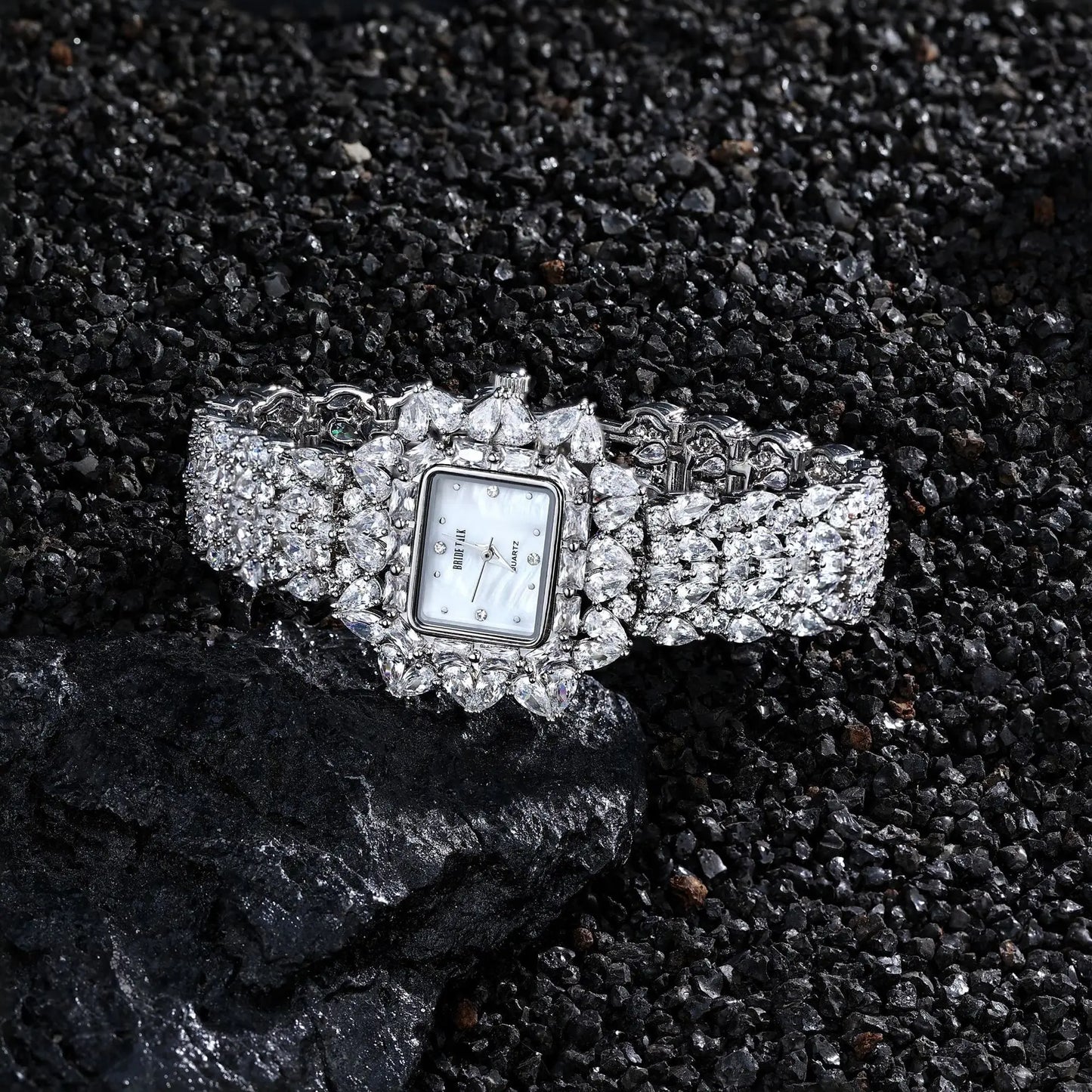 Silver watch with a decorative band on a dark textured surface