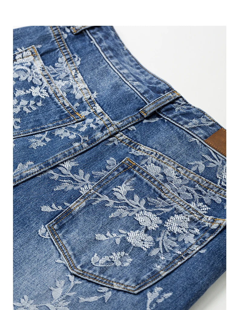 Blue denim jeans with floral embroidery on a white background