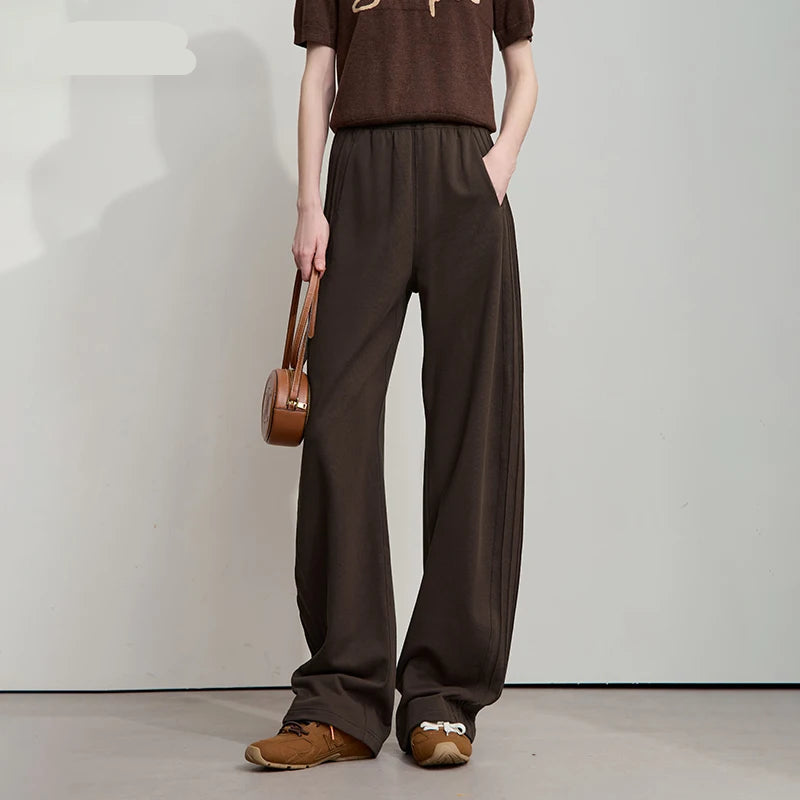 Person wearing brown outfit with wide-leg pants and holding a bag, standing against a plain background. - HER SHOP