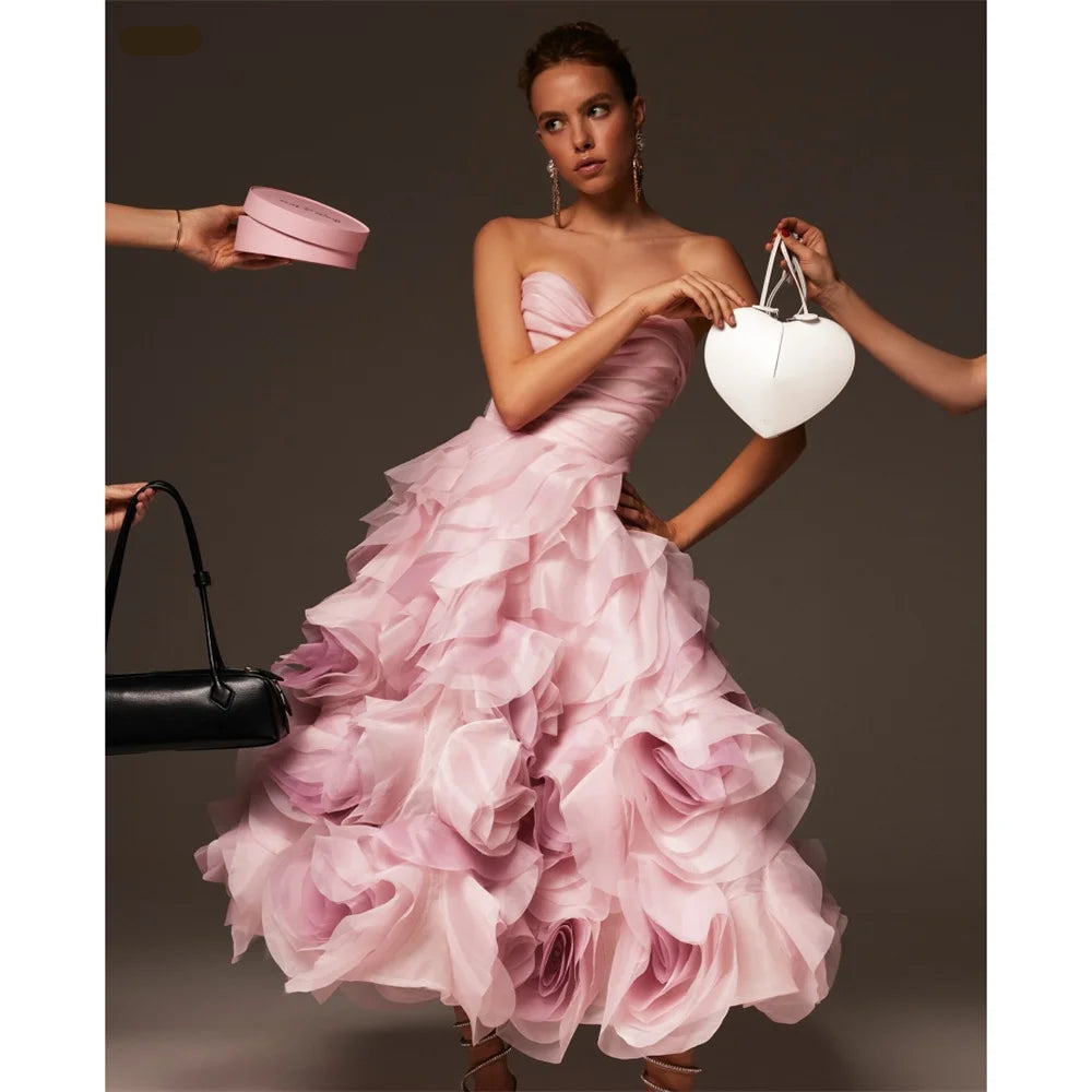 Woman in a pink strapless dress surrounded by handbags on a dark background