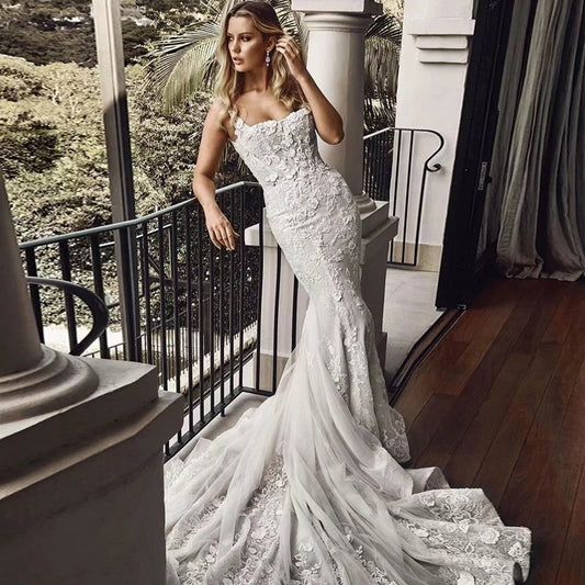 Woman in a white lace wedding dress standing outdoors with greenery in the background - HER SHOP