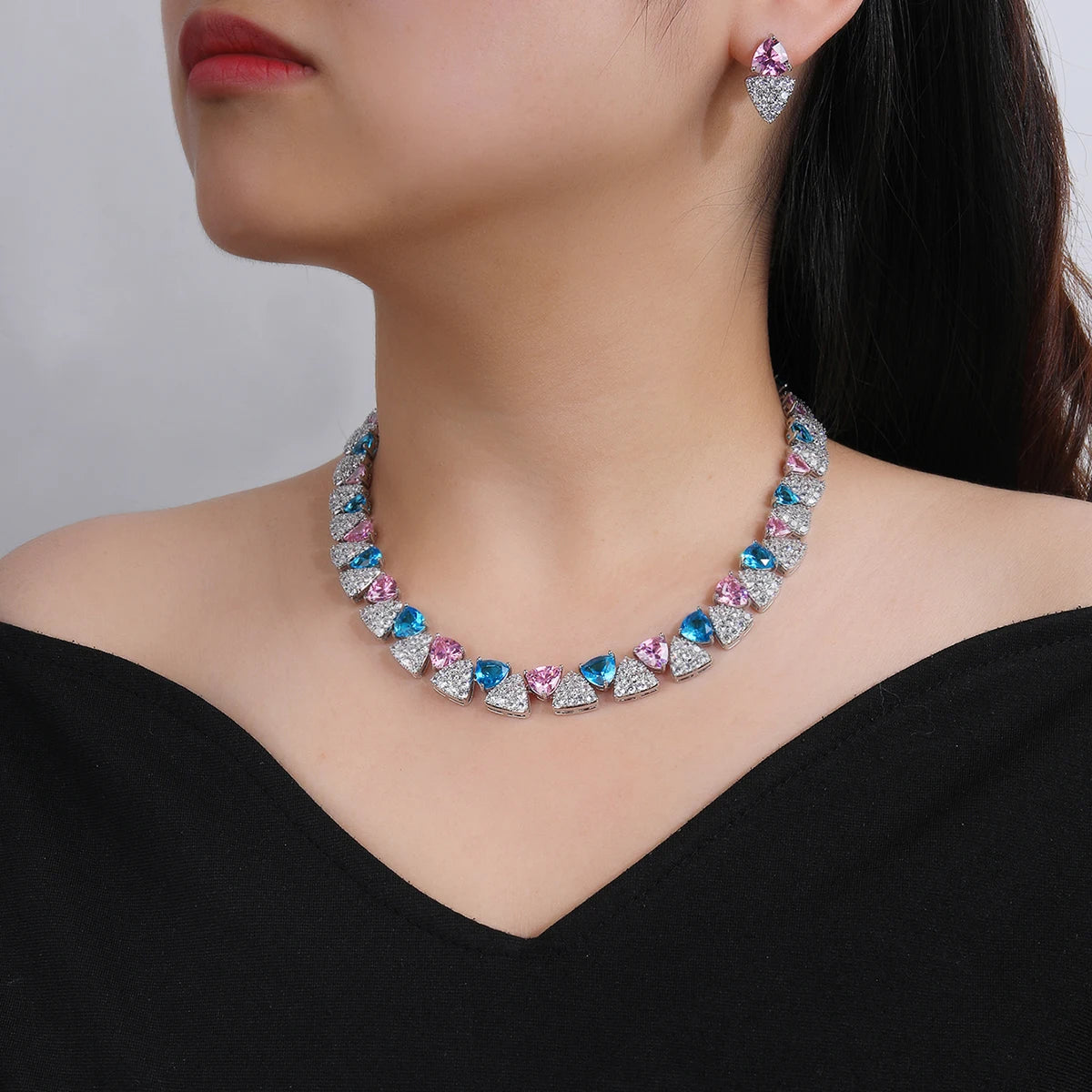 Multicolored gemstone necklace and earrings on a model against a neutral background