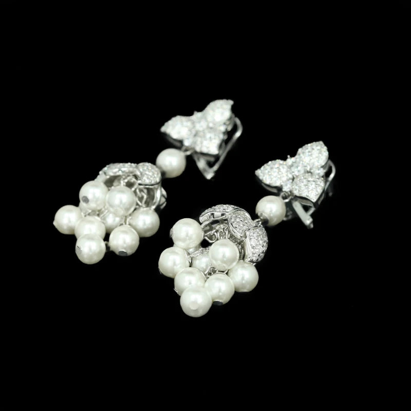 Pair of silver earrings with pearl drops on a black background