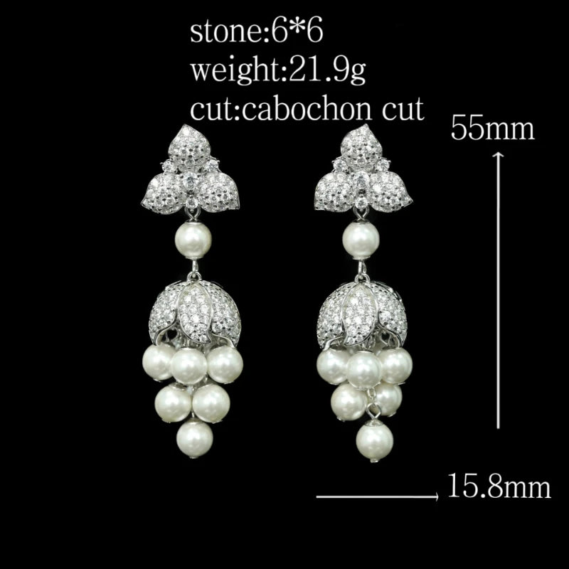 Pair of earrings with pearls and crystals on a black background, showing measurements.