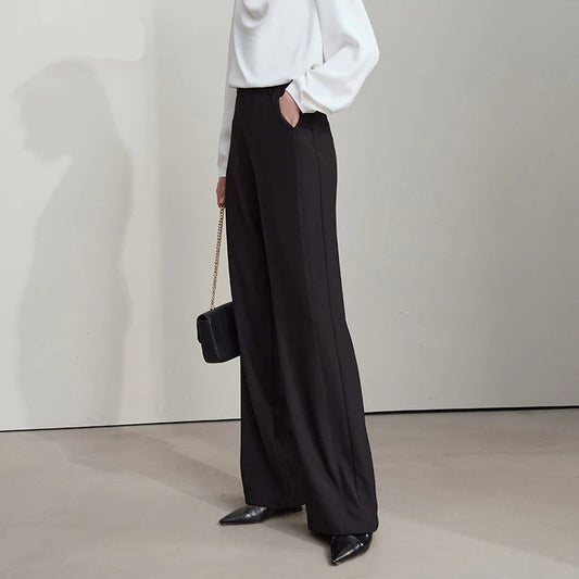 Person wearing a white shirt and black wide-leg pants with a handbag, standing against a plain background. - HER SHOP