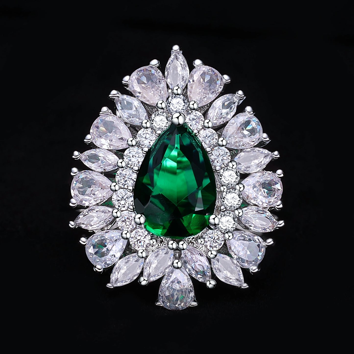 Jewelry with a green gemstone surrounded by clear stones on a black background