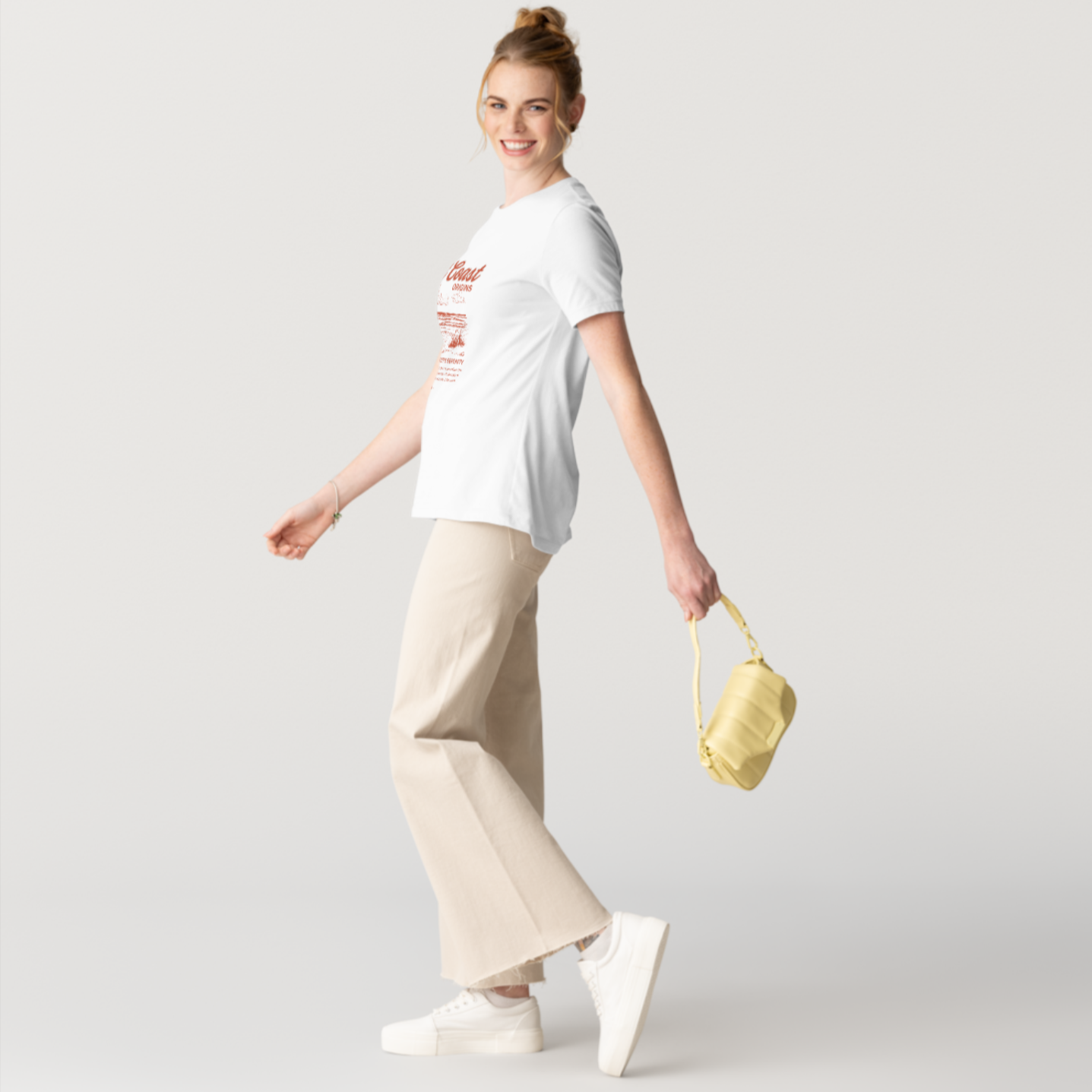Woman wearing a white t-shirt and beige pants, holding a yellow handbag on a light gray background