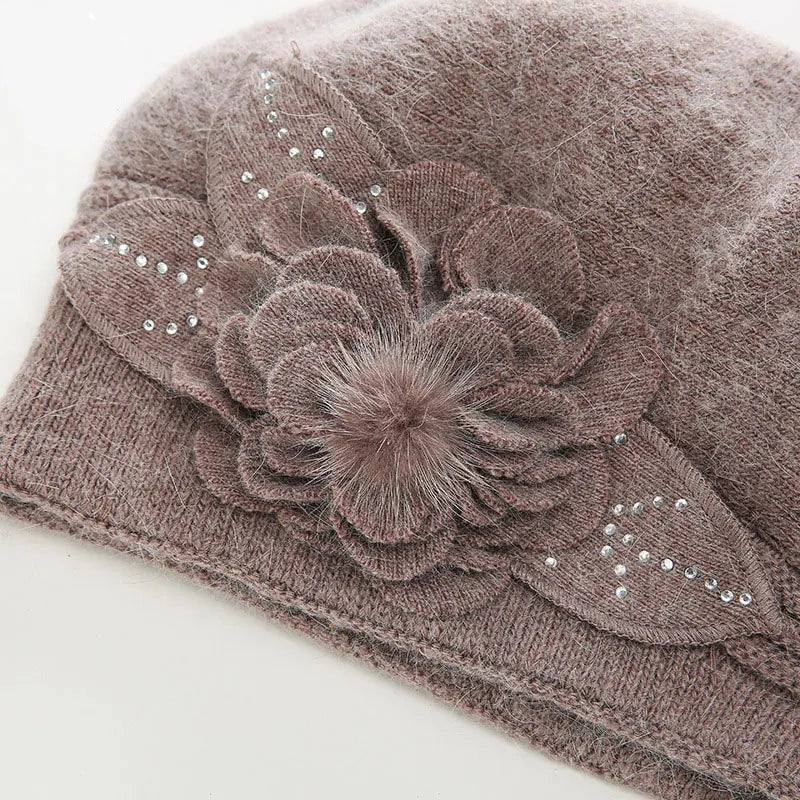 Brown knit headband with a decorative flower and embellishments on a white background