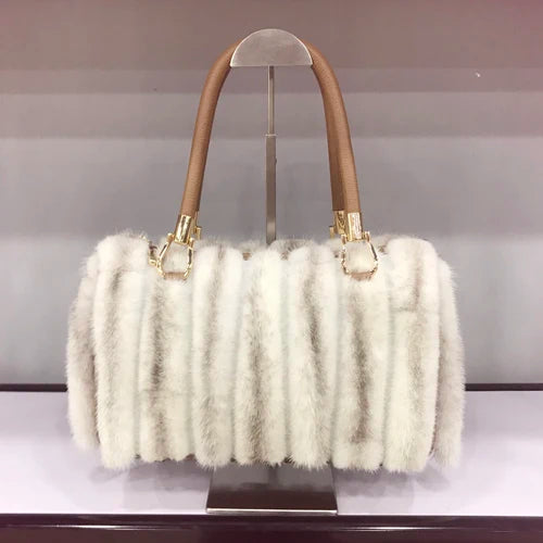 White fur handbag with brown handles on a stand, branded 'LLHPB FUR'.