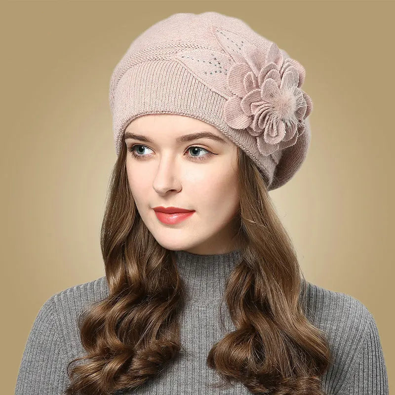 Woman wearing a pink knit beanie with a flower on a beige background