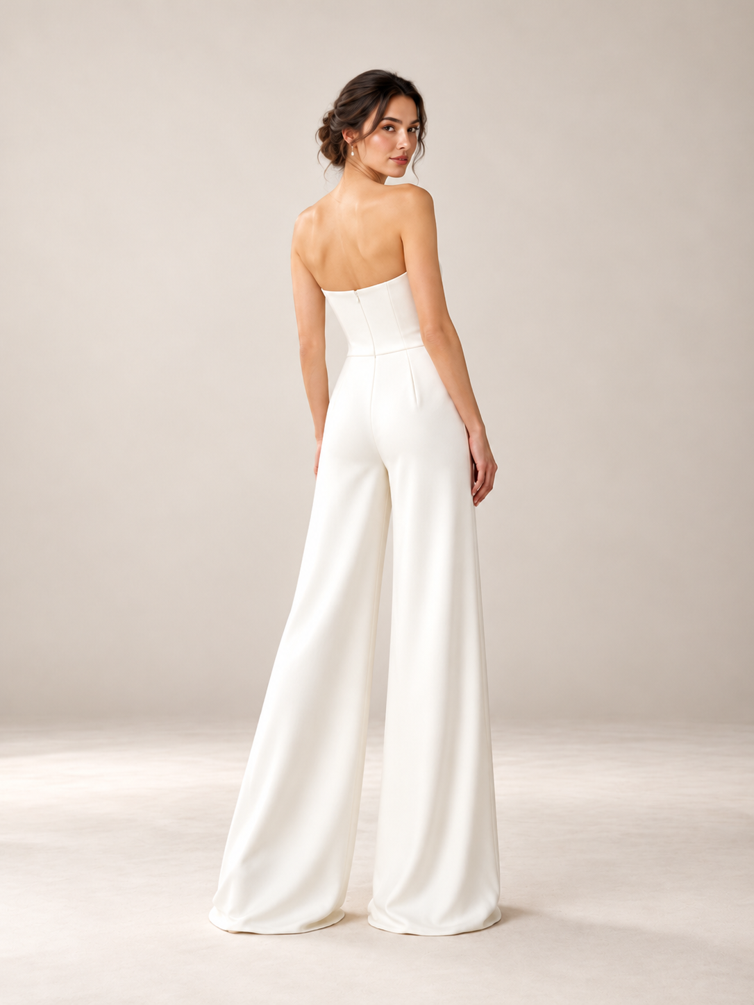 Back view of minimalist ivory wedding jumpsuit with fitted strapless bodice and flowing wide-leg pants