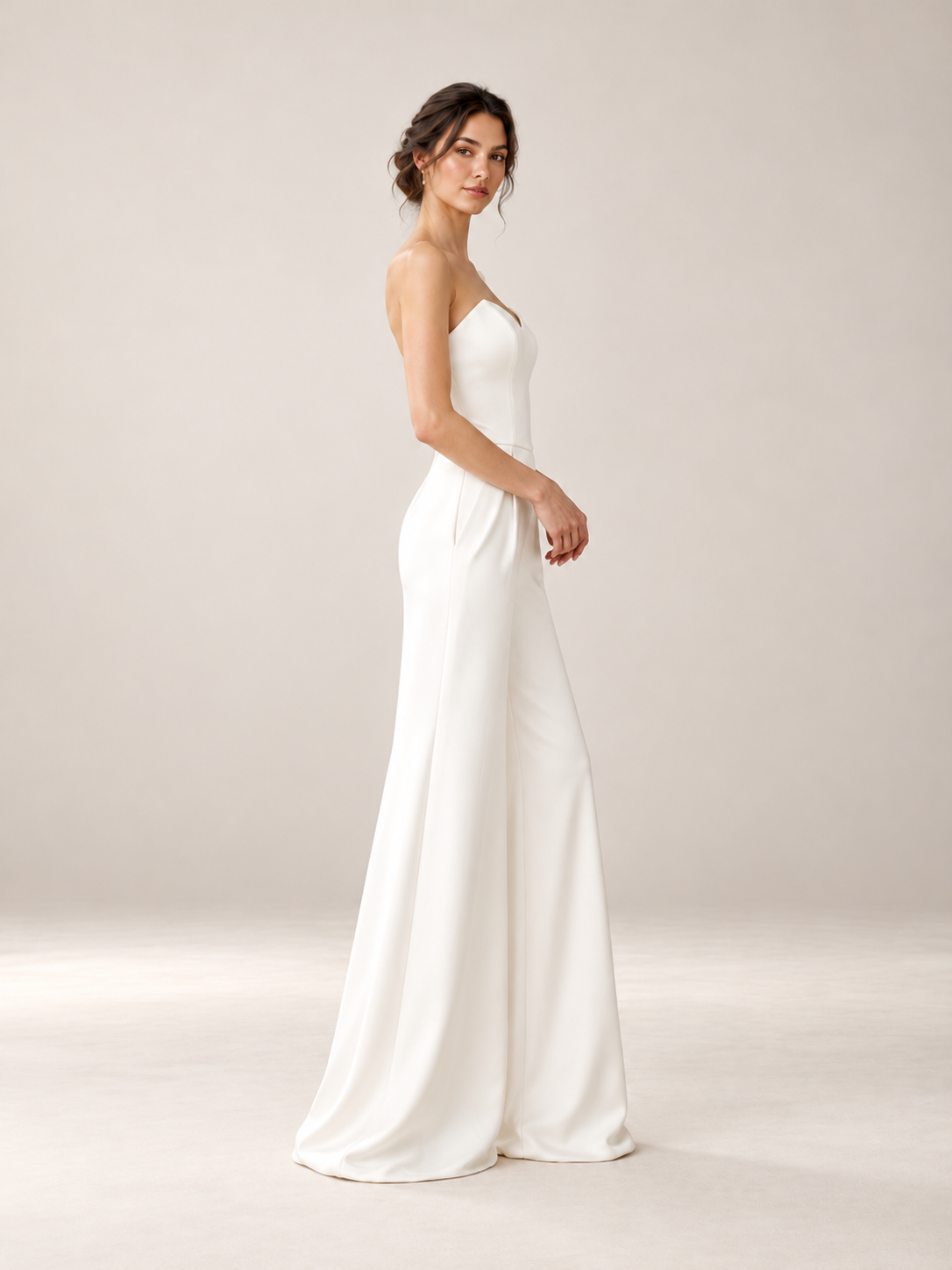 Back view of minimalist ivory wedding jumpsuit with fitted strapless bodice and flowing wide-leg pants