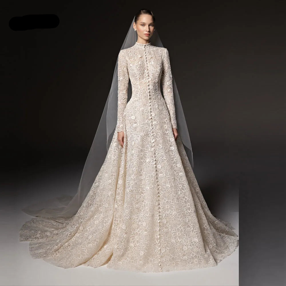 A model wears a high-neck, long-sleeved A-line modest wedding gown with intricate floral lace embroidery and a matching sheer veil. The brand name 'LISM' is visible in the top left corner against a dark studio background.