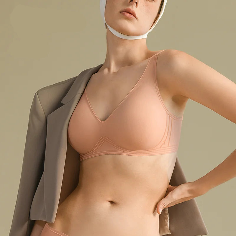 Woman wearing a peach-colored bra with a plain background and 'Sajiin' brand logo.