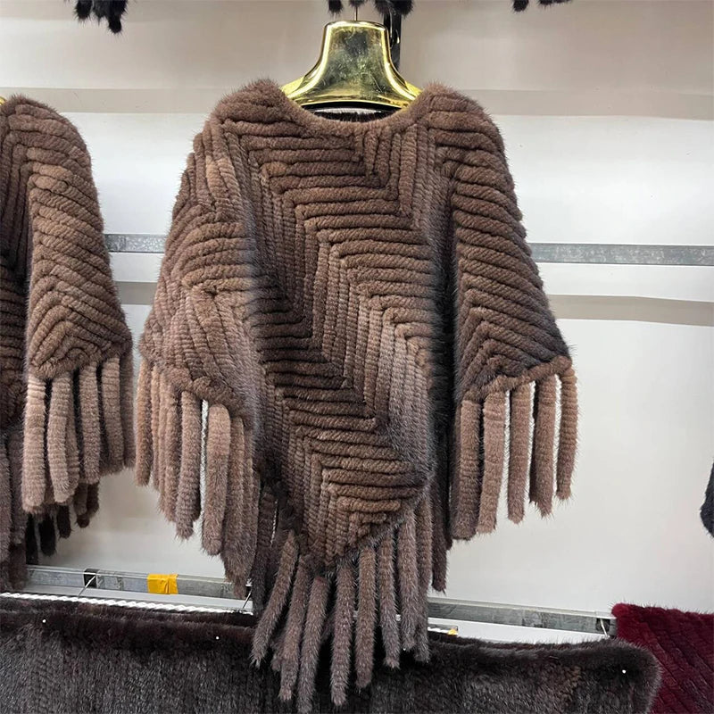 Brown knitted poncho with fringe on a hanger against a white background