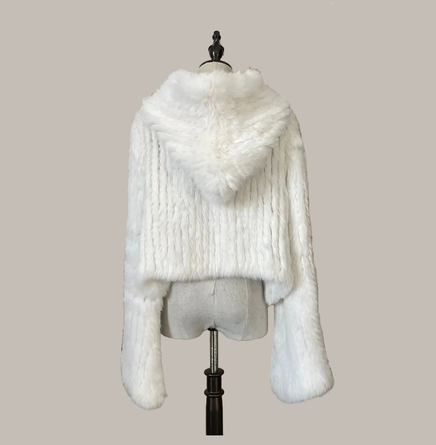 White fur coat on a mannequin against a decorative wall with floral elements.