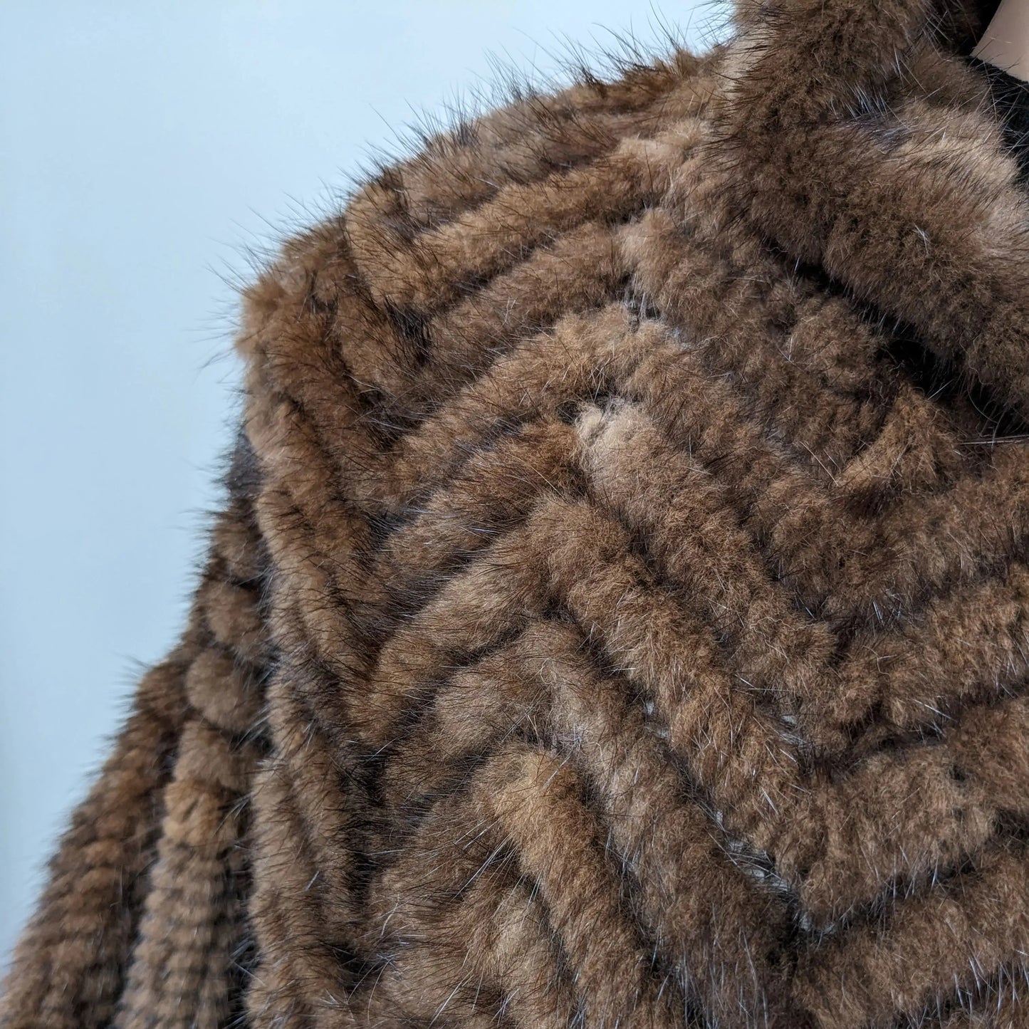 Close-up of a brown fur coat texture on a light blue background