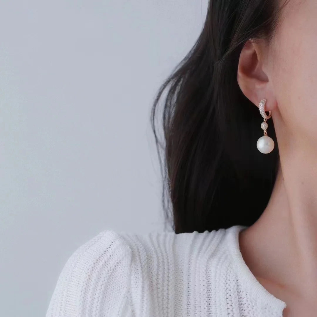 Pearl earring worn by a person against a plain background