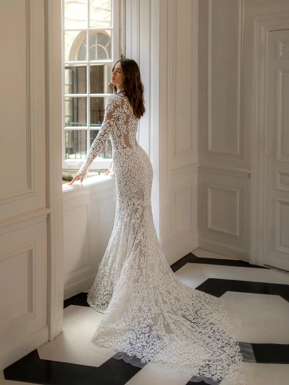 Back view of a long-sleeve lace mermaid wedding dress with a flowing bridal train