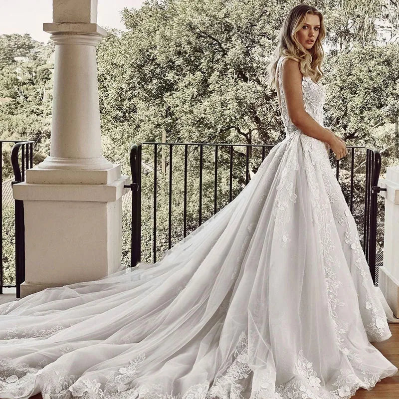 Woman in a white wedding dress standing on a balcony with greenery in the background
