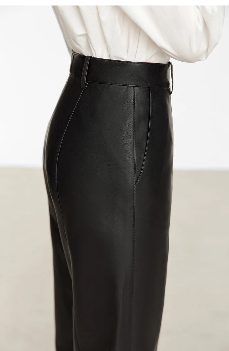 Person wearing black wide-leg pants and a white shirt on a gray background with 'Amii' branding.