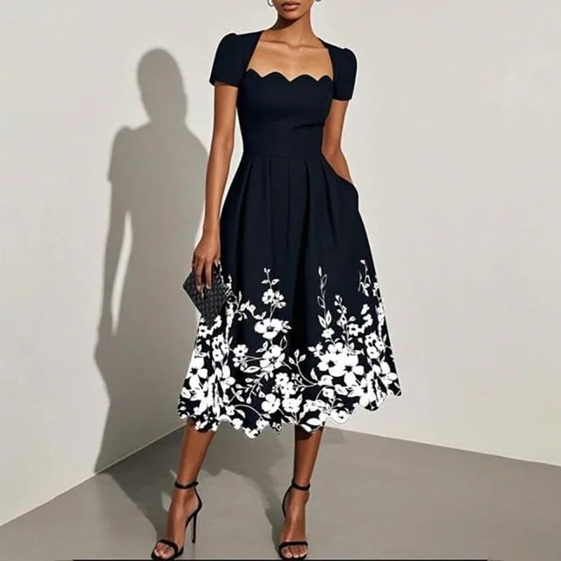 Woman wearing a black dress with white floral embroidery against a plain background