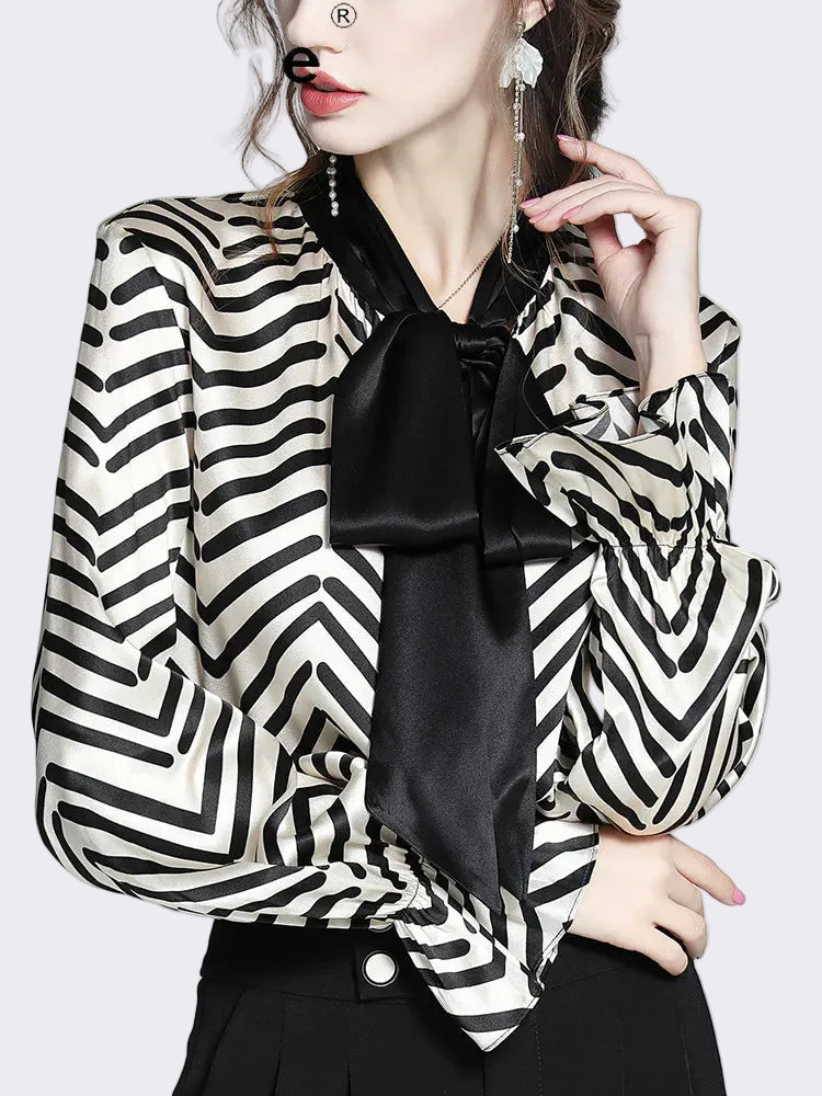 Woman wearing a black and white striped blazer with a black satin bow tie, brand 'tajiyane' visible.