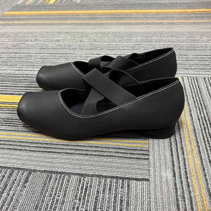 Black shoes with cross-straps on a patterned carpet, featuring the brand 'ddiezn'.