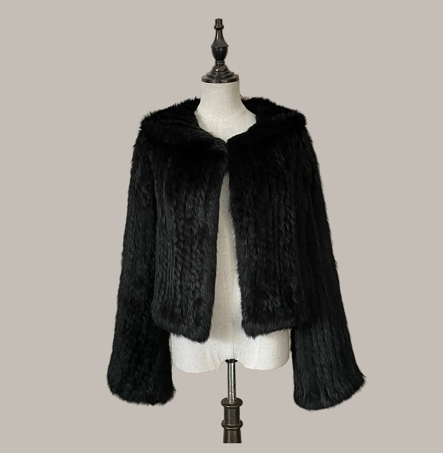 Black fur coat on a mannequin against a decorative wall with floral elements.