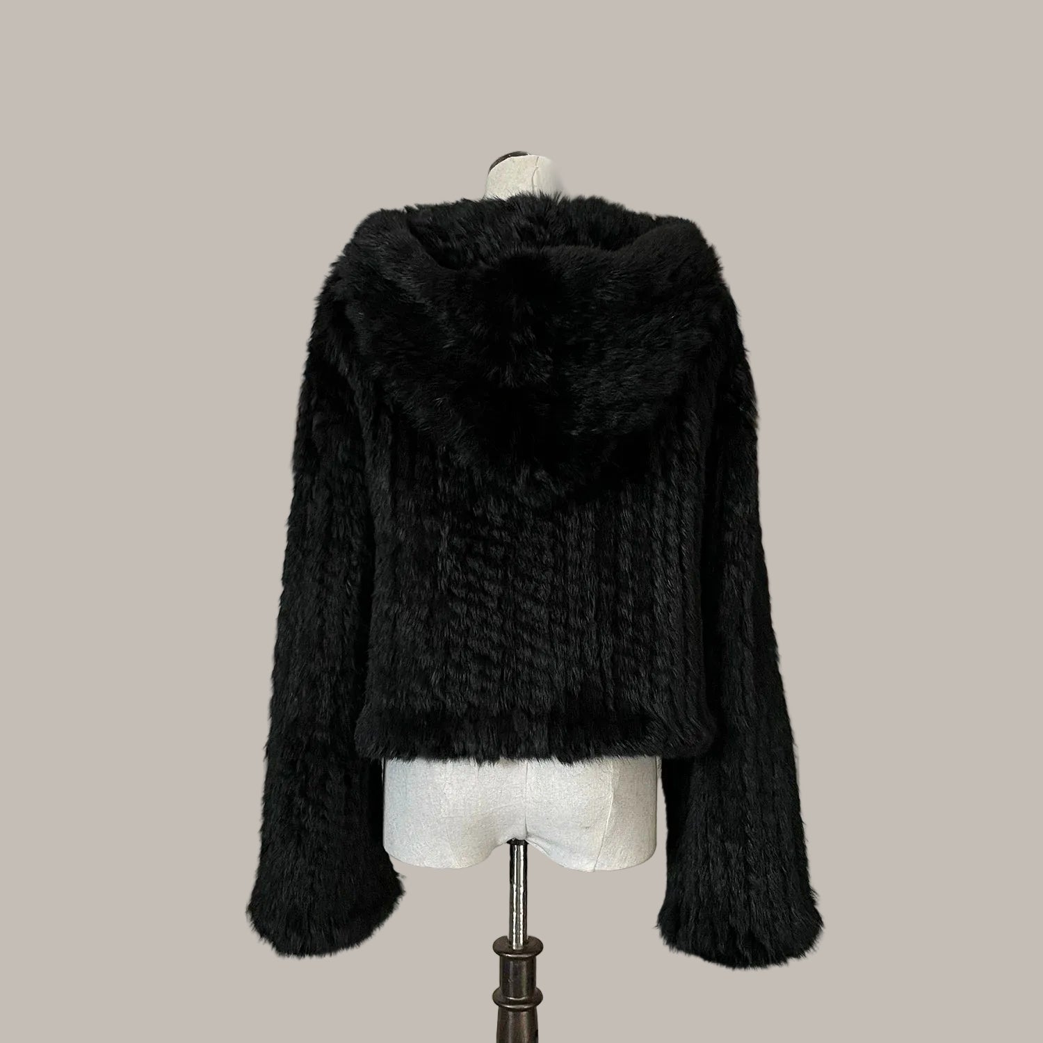 Black fur jacket on a mannequin against a decorative wall with floral elements.