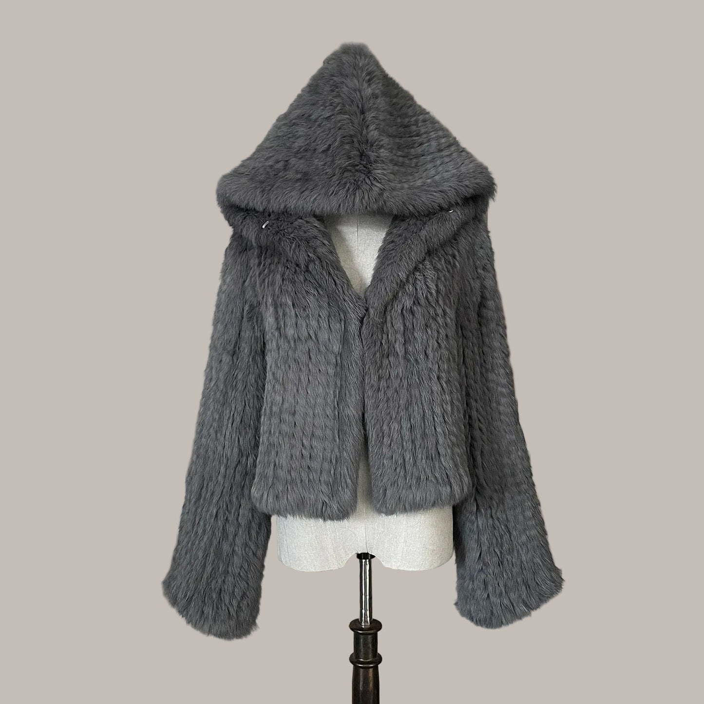 Gray knitted fur coat on a mannequin against a decorative background