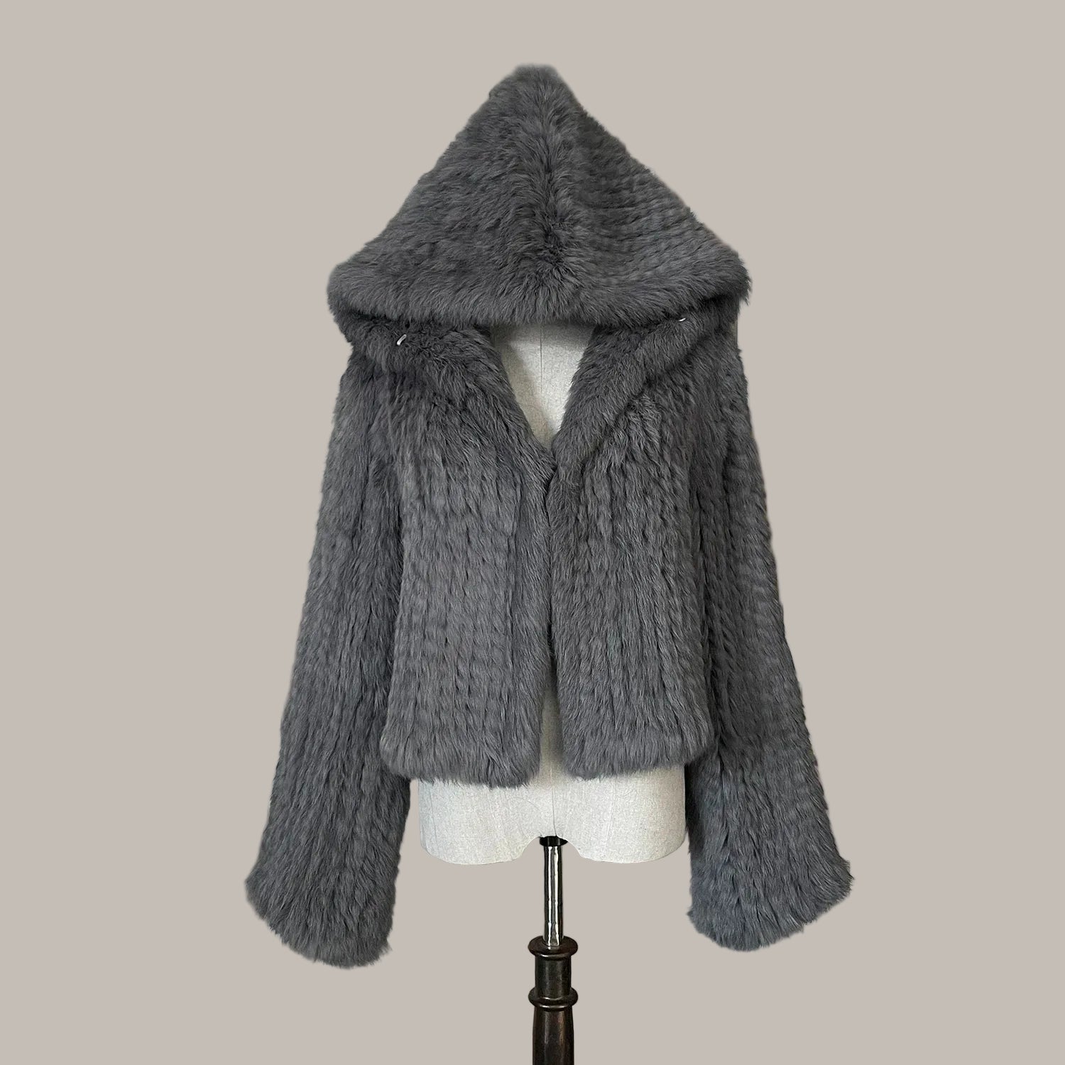 Gray knitted fur coat on a mannequin against a decorative background