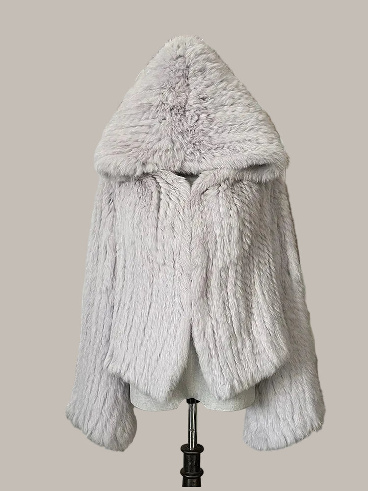 Gray fur coat on a mannequin against a decorative wall with floral elements.