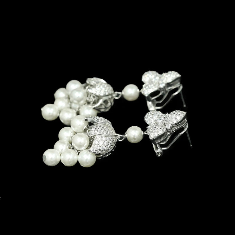 Pair of silver earrings with pearl drops on a black background