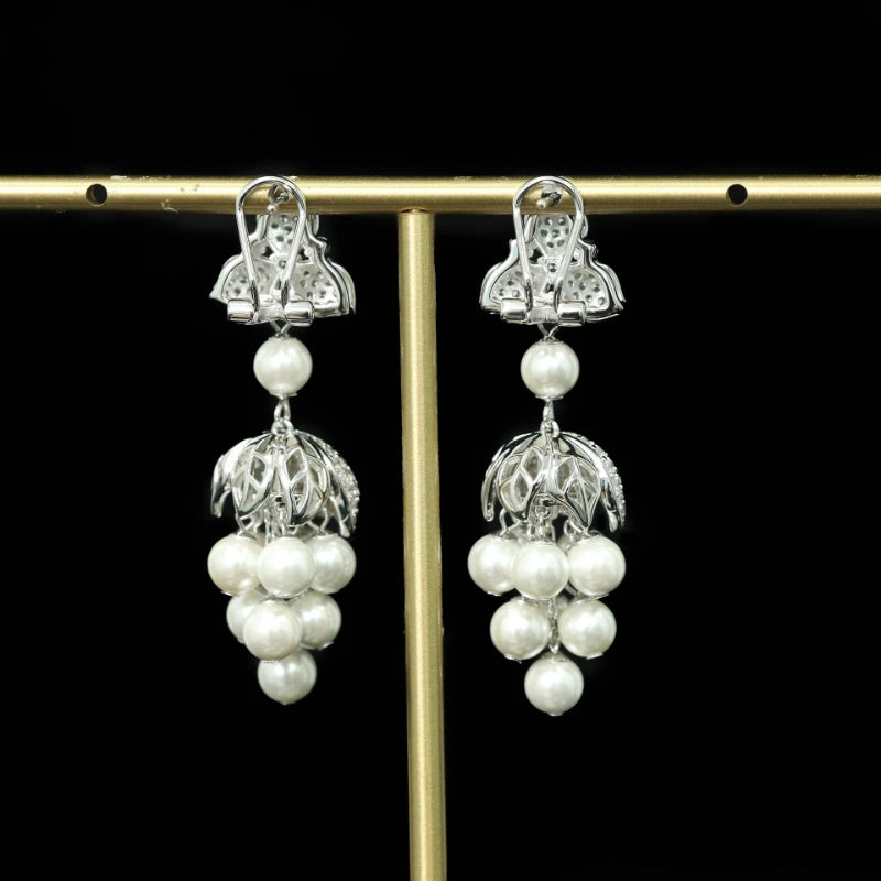 Pair of silver earrings with pearl drops on a black background