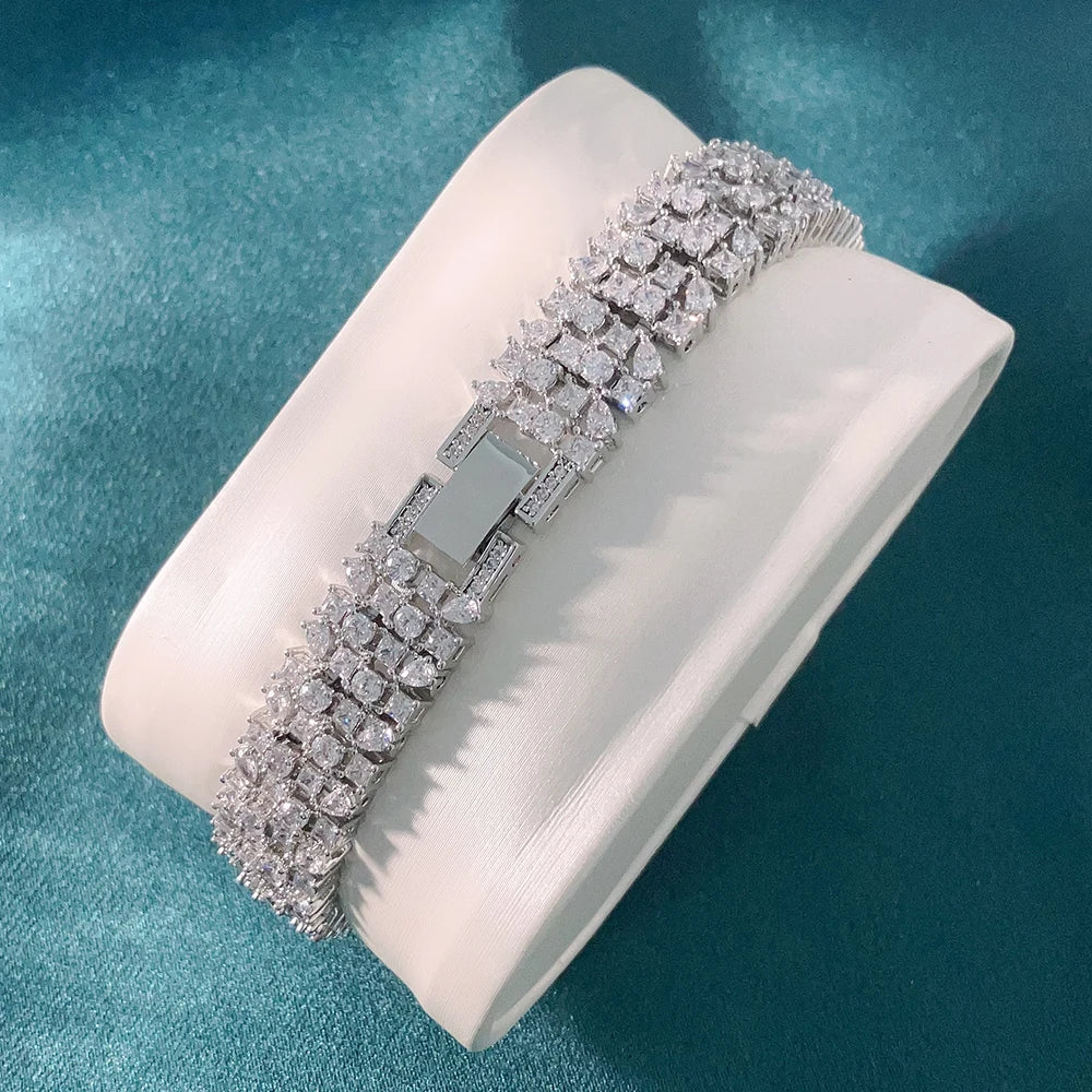 Silver bracelet on a white cushion against a teal background