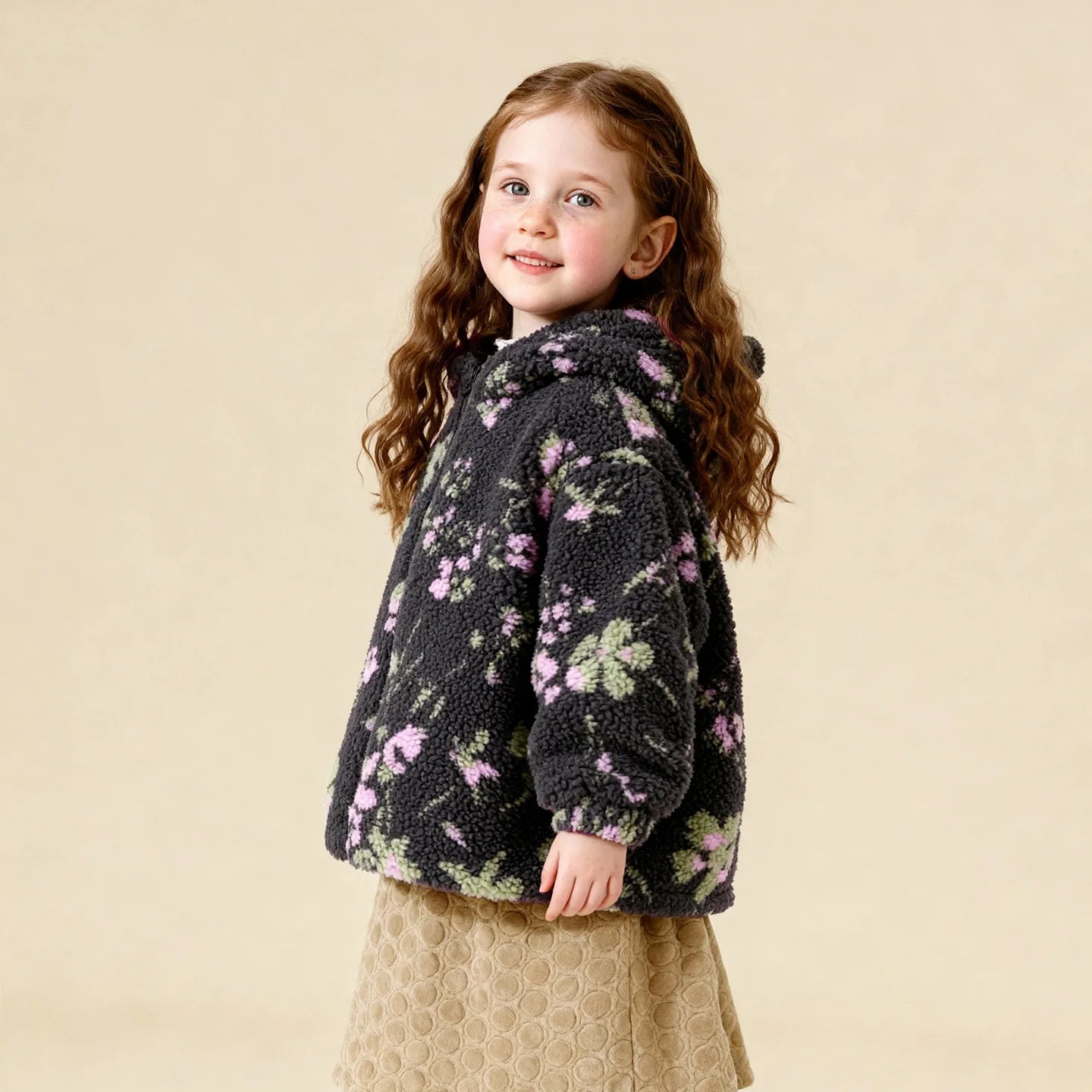 Young girl wearing a floral-patterned jacket with Amila logo in the corner