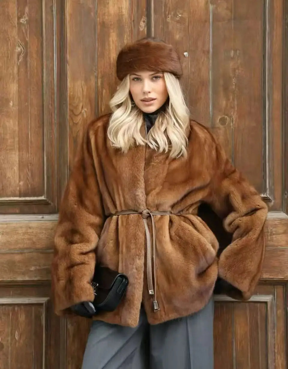 Woman wearing a brown fur coat and hat against a wooden background