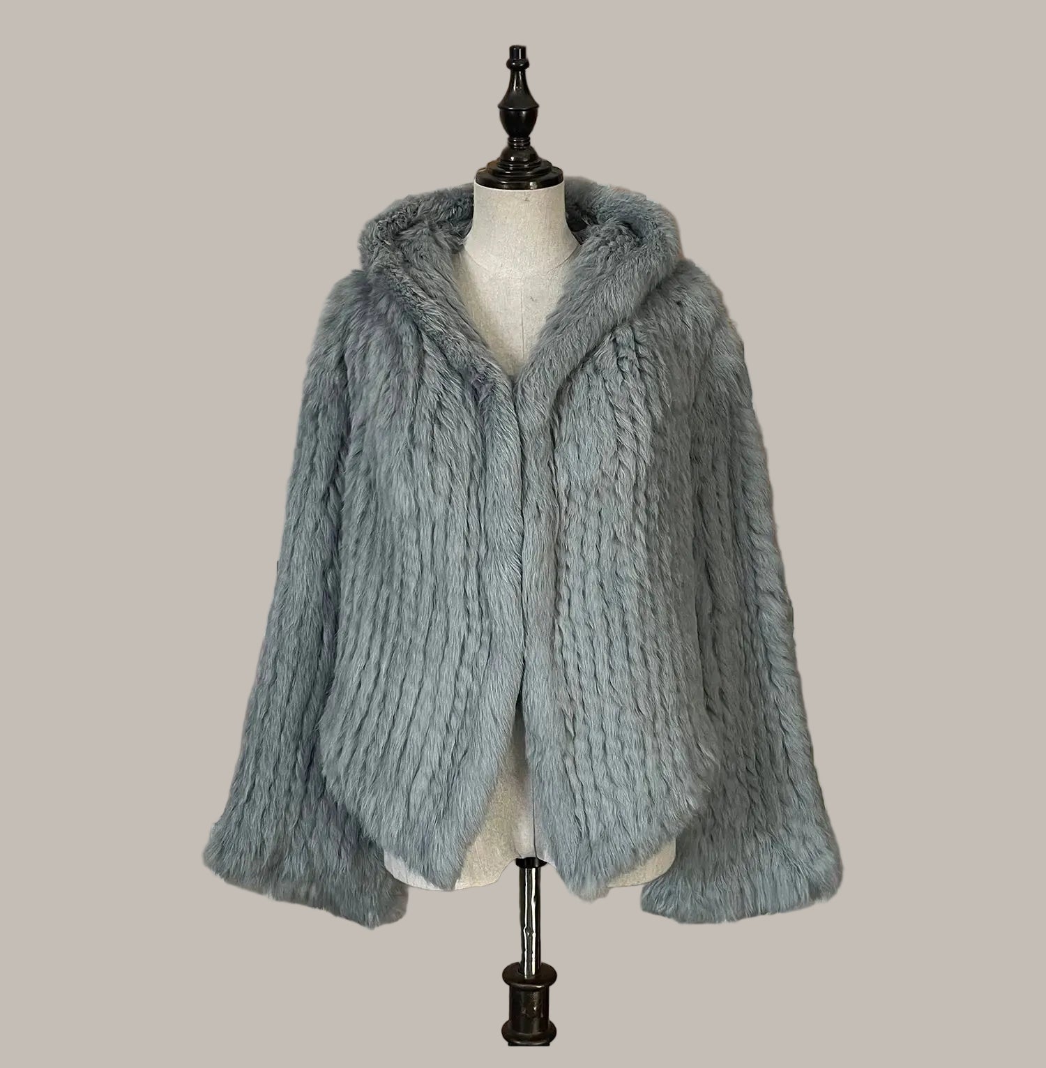 Gray knitted jacket on a mannequin against a decorative wall.