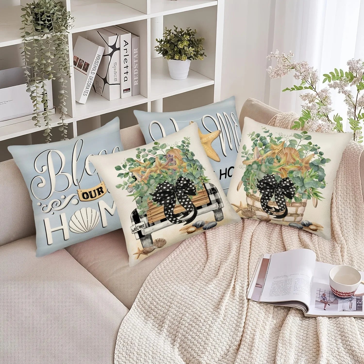 Decorative pillows with floral and text designs on a sofa with a book and mug.