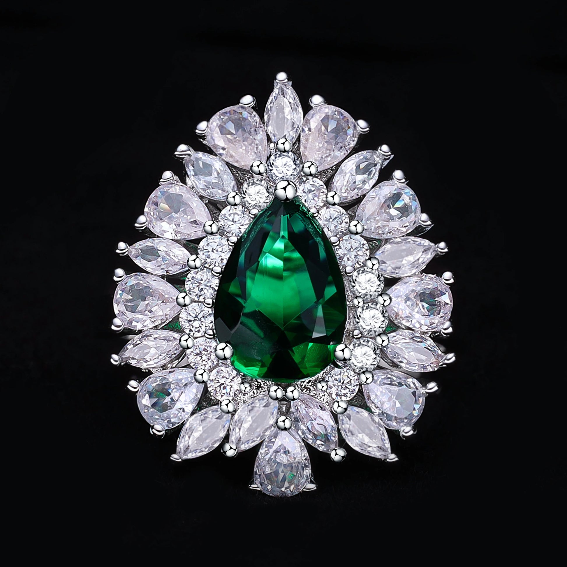 Jewelry with a green gemstone surrounded by clear stones on a black background
