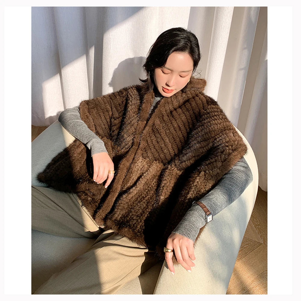 Person wearing a brown knitted poncho sitting on a chair with light curtains in the background - HER SHOP